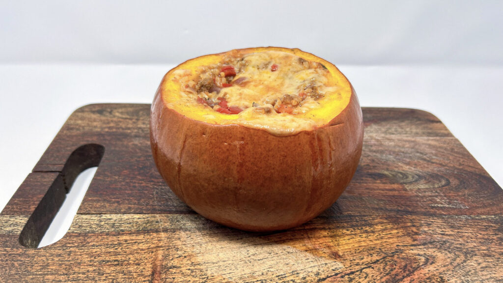 Lamb and Rice Stuffed Pumpkin, featuring a roasted pumpkin filled with a savory mixture of ground lamb, rice, and herbs, topped with melted Parmesan and garnished with fresh parsley.