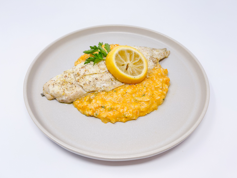 A beautifully plated dish of Lemon Garlic Pollock served with creamy Roasted Butternut Squash Risotto, garnished with fresh herbs and a lemon wedge, showcasing the vibrant colors and textures of the flaky fish and the rich, golden risotto.