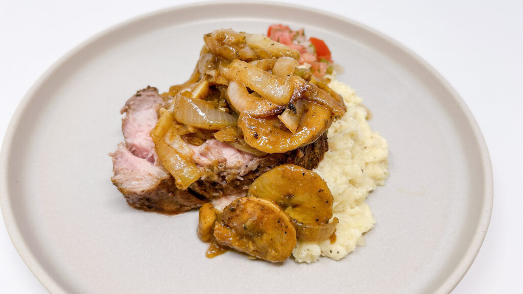 Plantain and Onion Braised Pork Loin Roast served on a platter, featuring tender, slow-cooked pork loin braised with caramelized onions and sweet plantains