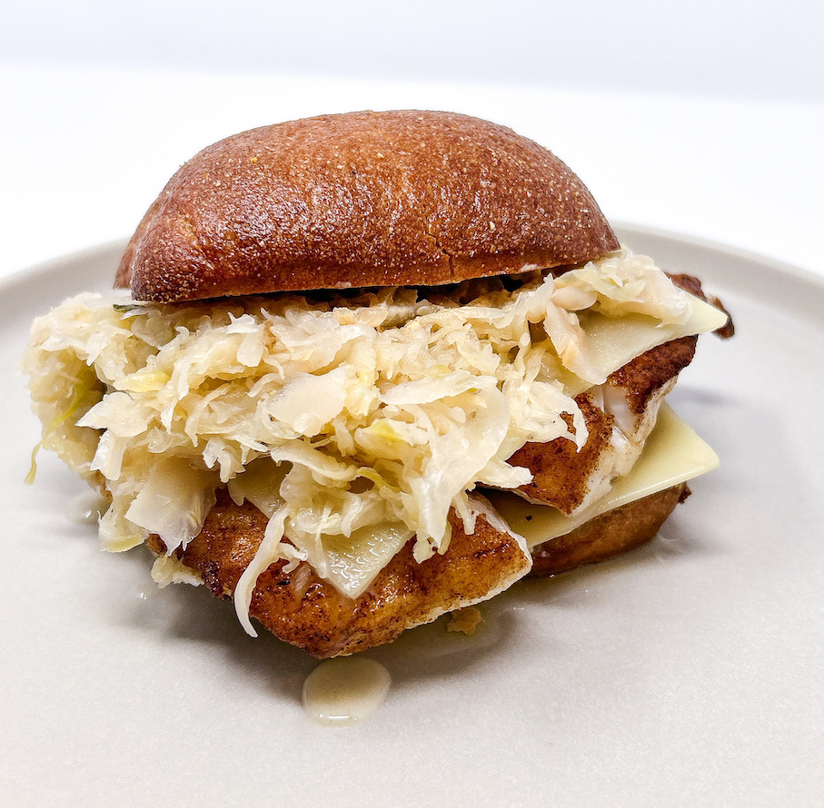Spicy Cajun Grouper Reuben served on toasted ciabatta, featuring blackened Cajun-spiced grouper, tangy sauerkraut, melted Swiss cheese, and creamy thousand island dressing for a bold and flavorful twist on the classic sandwich
