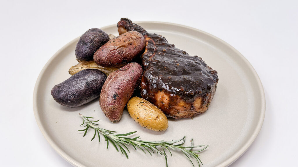 Juicy Apple Cider-Whiskey Glazed Pork Chops served on a plate, featuring tender pork chops coated in a sweet and tangy apple cider-whiskey glaze, with a caramelized finish for a bold, flavorful dish