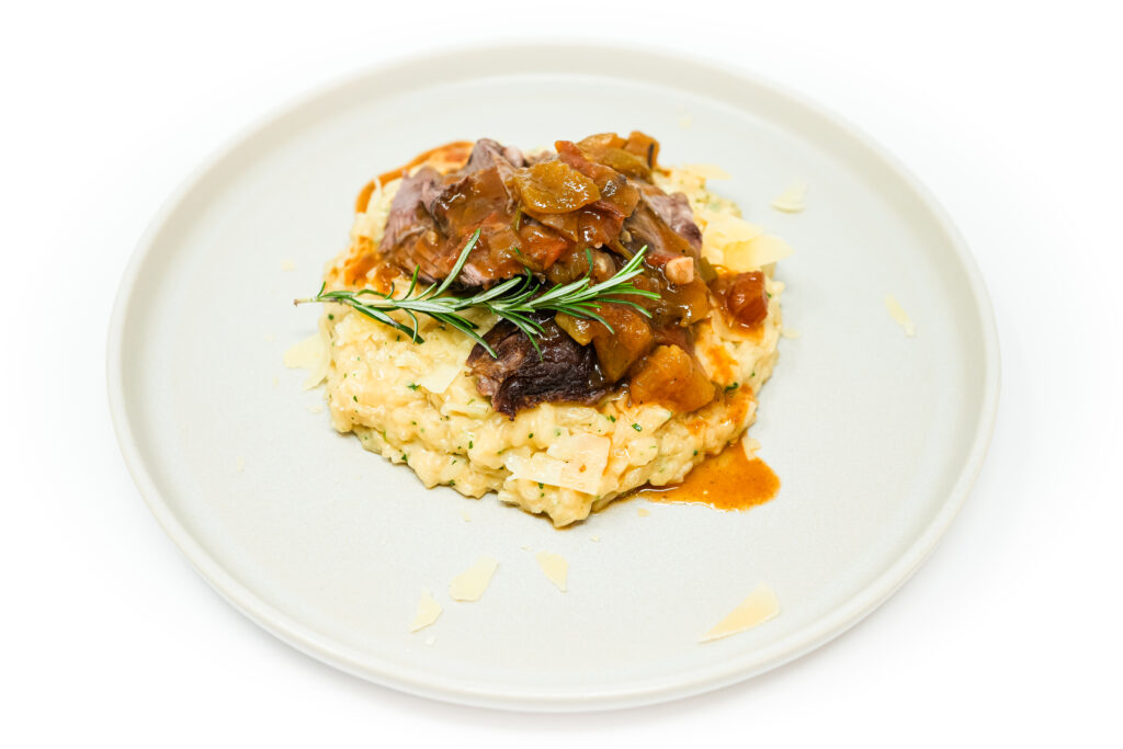 Heirloom Tomato Braised Lamb Shank served on a plate, featuring tender, slow-braised lamb shank in a rich heirloom tomato sauce, garnished with fresh herbs for a flavorful and comforting dish.
