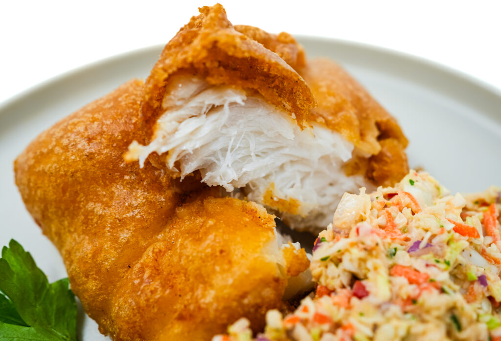 Crispy Beer-Battered Cusk served on a plate alongside a creamy coleslaw, featuring golden, crunchy cusk fillets with a light beer batter, paired with a refreshing slaw for a balanced and flavorful dish.