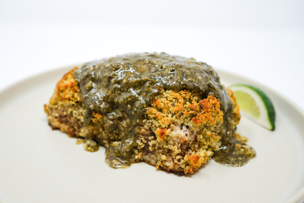 Chimichurri Crusted Striped Bass served on a plate, featuring a crispy herb-crusted fillet topped with vibrant chimichurri sauce, accompanied by fresh herbs for a flavorful, zesty seafood dish