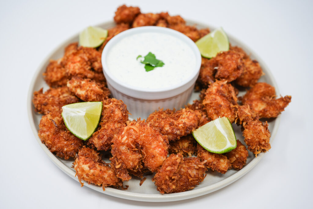 Crispy Coconut Shrimp with Cilantro Lime Crema Dipping Sauce served on a plate, featuring golden, crunchy coconut-coated shrimp paired with a tangy cilantro lime crema dipping sauce, creating a perfect balance of tropical flavors and zesty freshness