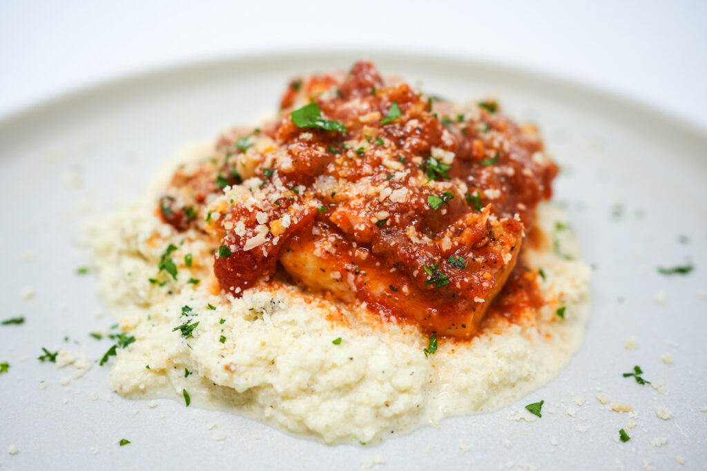 San Marzano Tomato Poached Cod served on a plate, featuring tender cod fillets gently poached in a rich, flavorful San Marzano tomato sauce, garnished with fresh herbs for a vibrant and savory dish