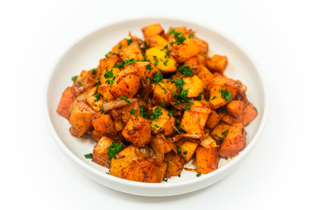 Paprika roasted potatoes served on a plate, featuring golden, crispy potatoes seasoned with smoky paprika and topped with sweet, caramelized onions for a flavorful side dish