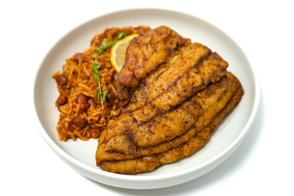 Plate of Redfish, Red Beans, and Rice featuring a perfectly seared redfish fillet atop a bed of seasoned rice and creamy red beans