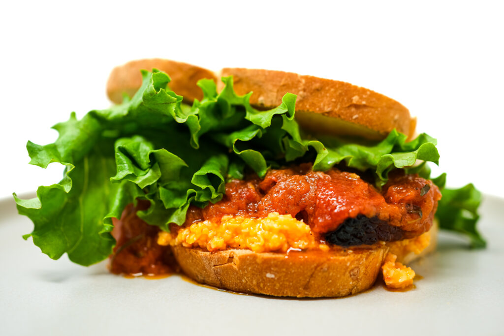 Crispy Pork Belly and Tomato Confit BLT with pimento cheese, featuring layers of golden pork belly, juicy tomato confit, and creamy pimento cheese on toasted bread.