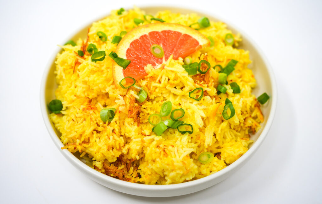 Orange Coconut Saffron Rice served in a bowl, featuring fluffy, golden-yellow rice infused with saffron, zesty orange, and rich coconut flavors, garnished with a sprinkle of fresh herbs.