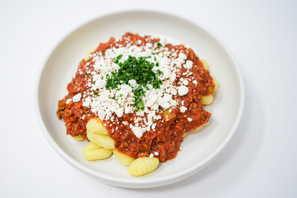 Mediterranean-Inspired Ground Lamb Ragu served over gnocchi pasta, topped with crumbled goat cheese and fresh parsley.