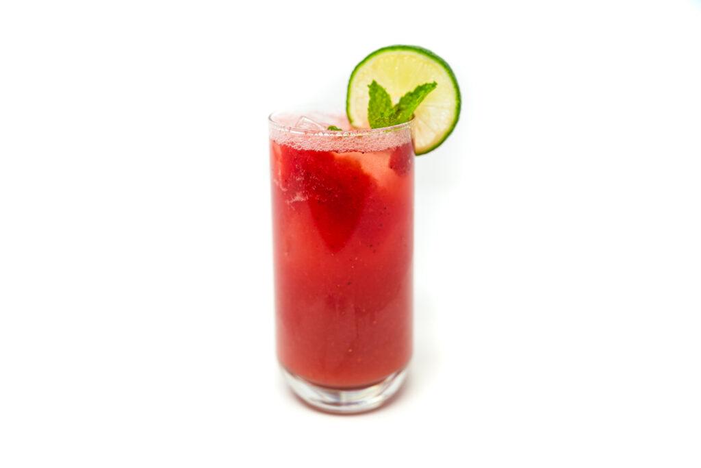 A vibrant pink Watermelon Mint Tequila Fizz in a clear glass, garnished with fresh mint leaves and a lime wedge, with fizzy bubbles rising to the top.