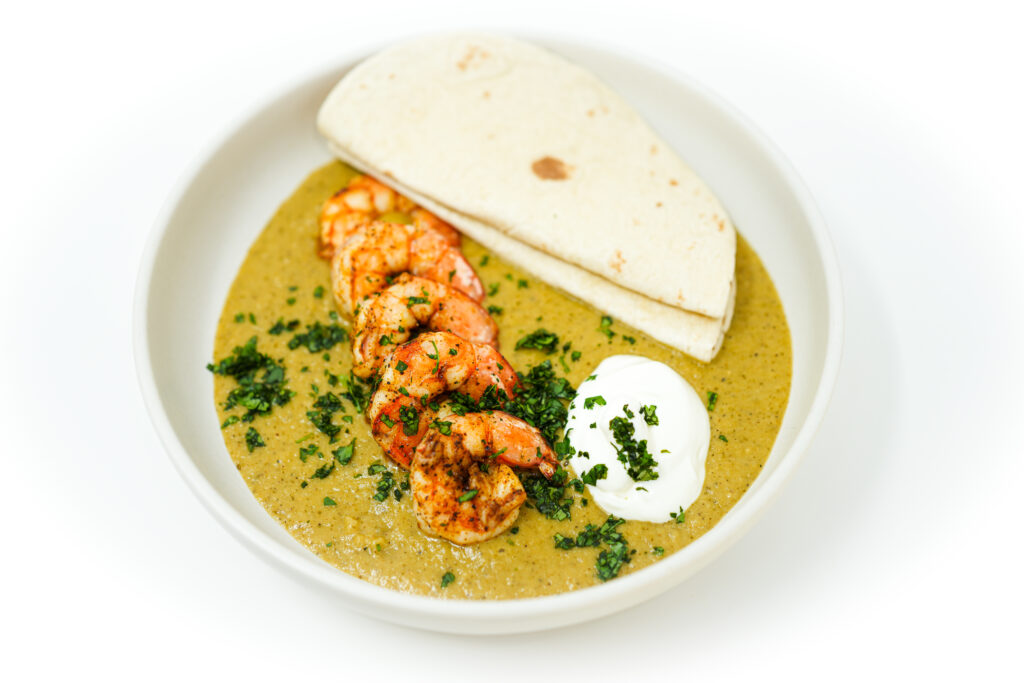 A vibrant image of Spicy Tomatillo Shrimp Bowls, showcasing juicy broiled shrimp on a bright green tomatillo sauce, garnished with fresh cilantro and a dollop of sour cream, accompanied by a side of warm tortillas.