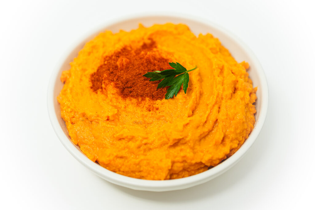 A bowl of creamy Paprika Mashed Sweet Potatoes, garnished with a sprinkle of smoked paprika and freshly chopped parsley.