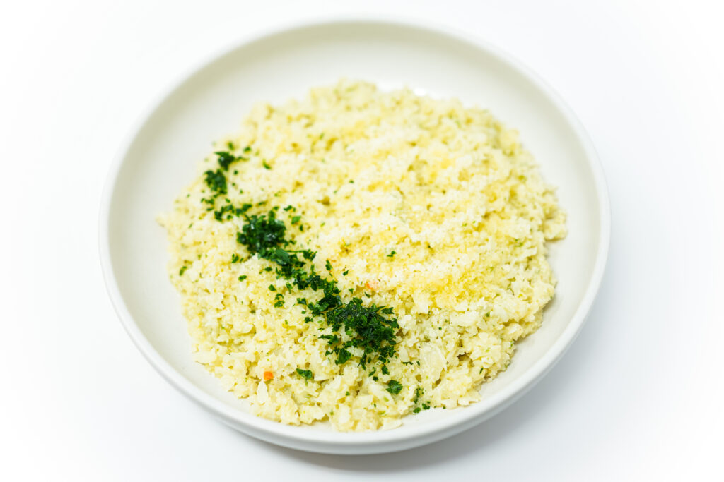 A bowl of Truffle Cauliflower Rice Risotto garnished with fresh parsley and drizzled with truffle oil.