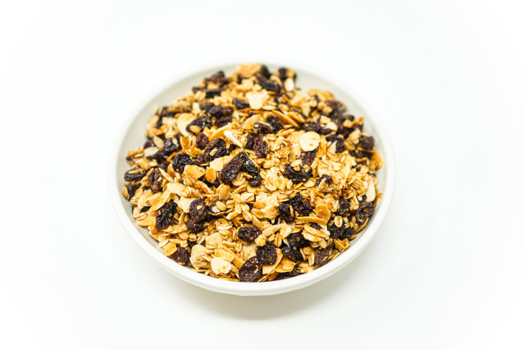 A bowl of homemade Brown Sugar Raisin Granola featuring rolled oats, almond slices, and raisins, with a rich brown sugar and cinnamon coating.