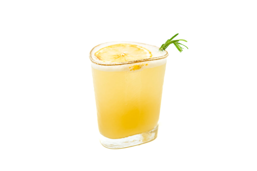 A Lavender Whiskey Sour garnished with a lemon twist and a sprig of lavender, served in a glass with a smooth, frothy top.
