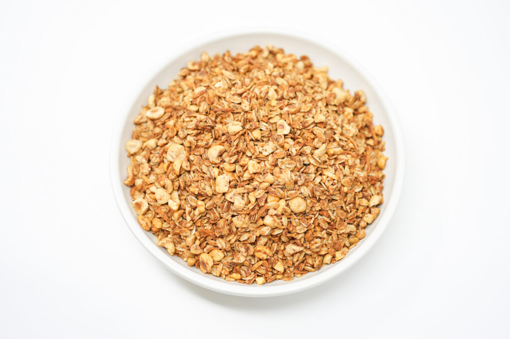 A bowl of Peanut Butter Hazelnut Granola with oats, roasted hazelnuts, and coconut flakes.