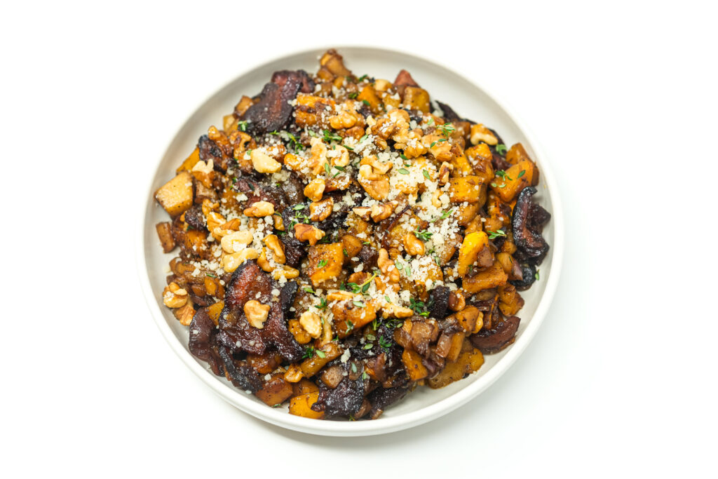 A serving of Maple Bacon Carnival Squash and Apple Hash, featuring roasted carnival squash, diced apples, crispy bacon, and garnished with toasted walnuts, Parmesan cheese, and fresh thyme.