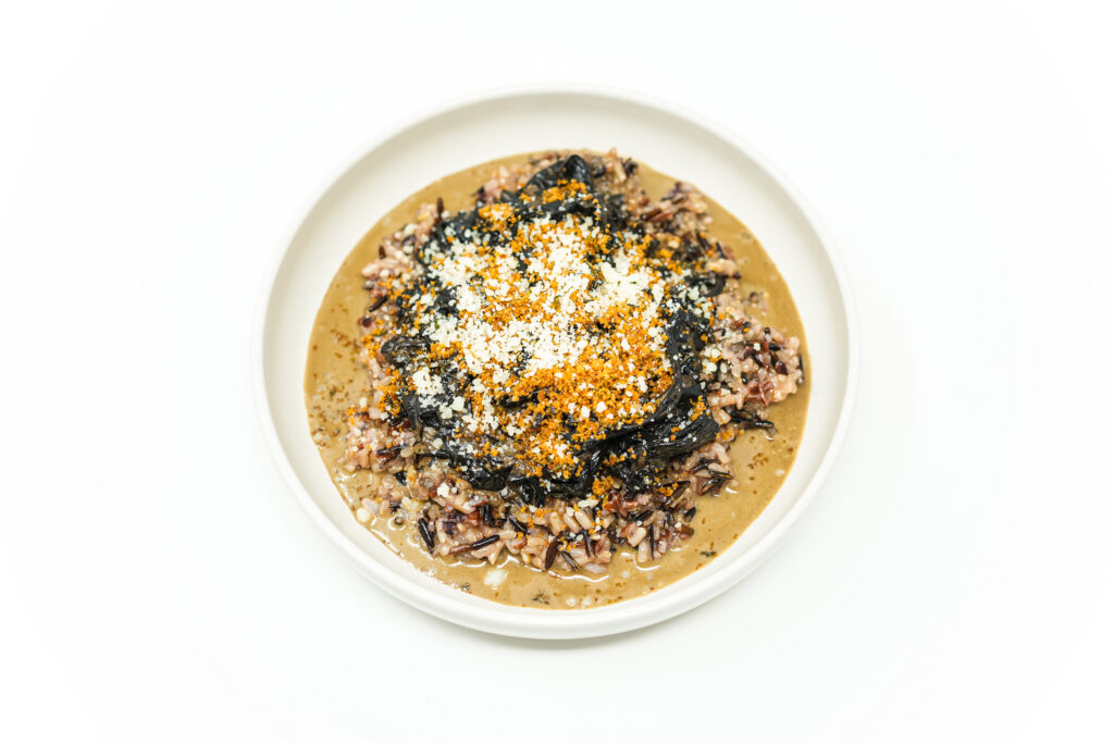 A bowl of Black Trumpet Mushroom recipe with Cream Sauce served over wild rice, garnished with golden toasted breadcrumbs, fresh thyme, and grated Parmesan cheese.