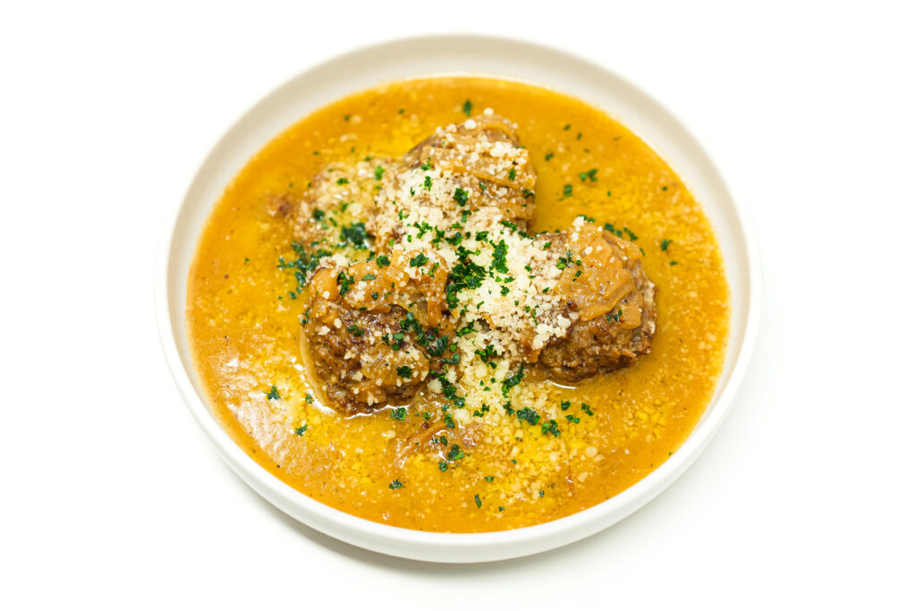 Plate of French Onion Meatballs in a rich caramelized onion sauce, garnished with fresh parsley and grated Parmesan.