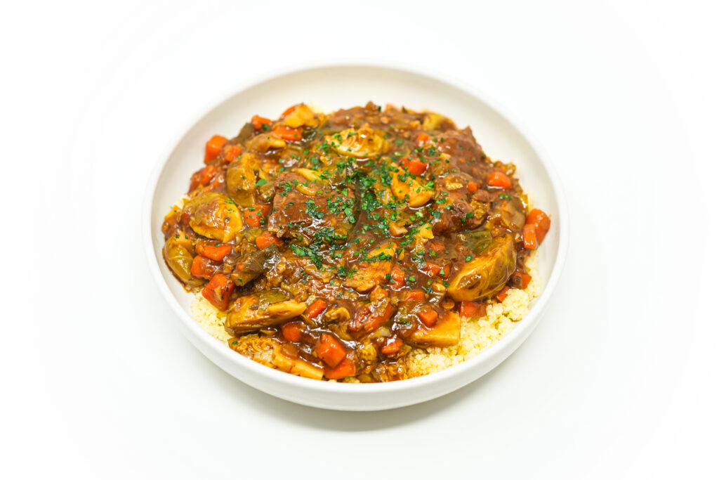 A bowl of Guinness Beef and Brussels Sprouts Stew featuring tender beef, roasted Brussels sprouts, carrots, and a rich, dark stout-infused broth, garnished with fresh parsley.