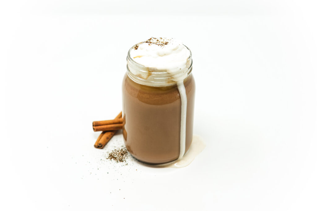 Close-up of Cinnamon and Chili Pepper Infused Hot Chocolate topped with cinnamon-chipotle whipped cream, served in a mug with a cinnamon stick garnish.