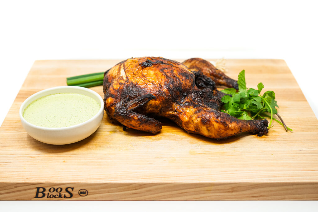 Peruvian-Style Roasted Chicken served with a vibrant green Aji Verde sauce made with cilantro, avocado, and lime, garnished with fresh herbs.