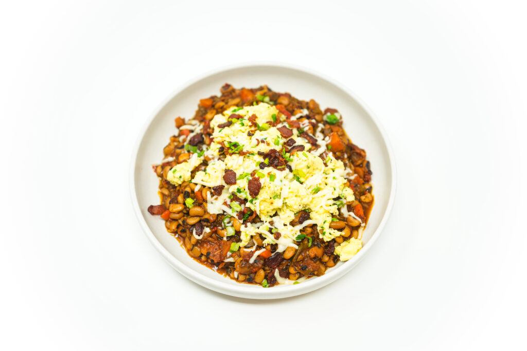 Bowl of Hoppin’ Johnny breakfast hash made with black-eyed peas, bacon, scrambled eggs, pepper jack cheese, and scallions.