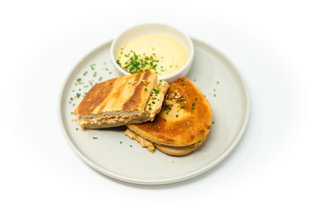 Crispy, golden-brown naan sandwich filled with creamy crab rangoon-inspired filling, served with a side of blended caramelized shallot aioli.