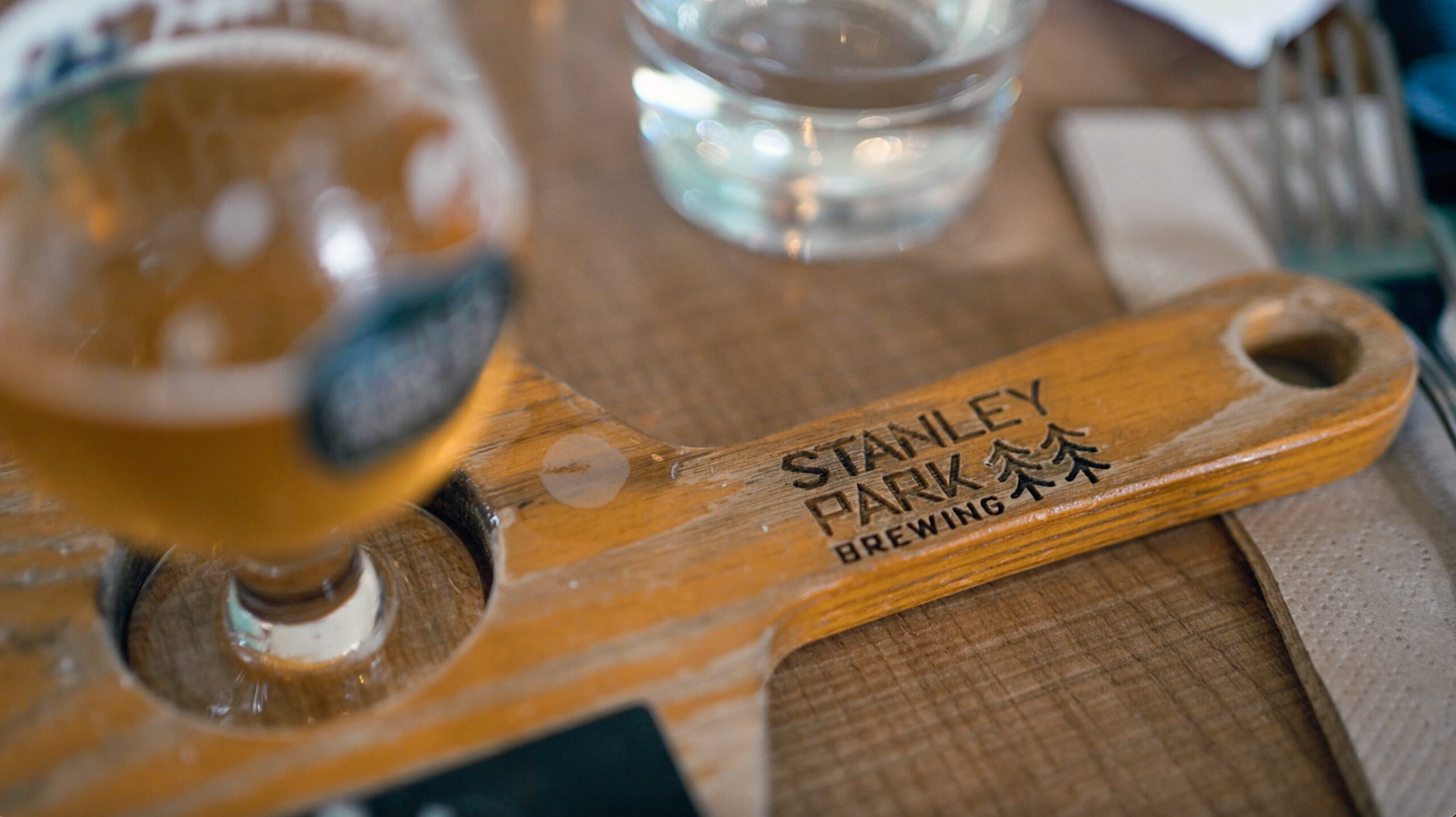 Beer glass and coaster from Stanley Park Brewing on a wooden table.