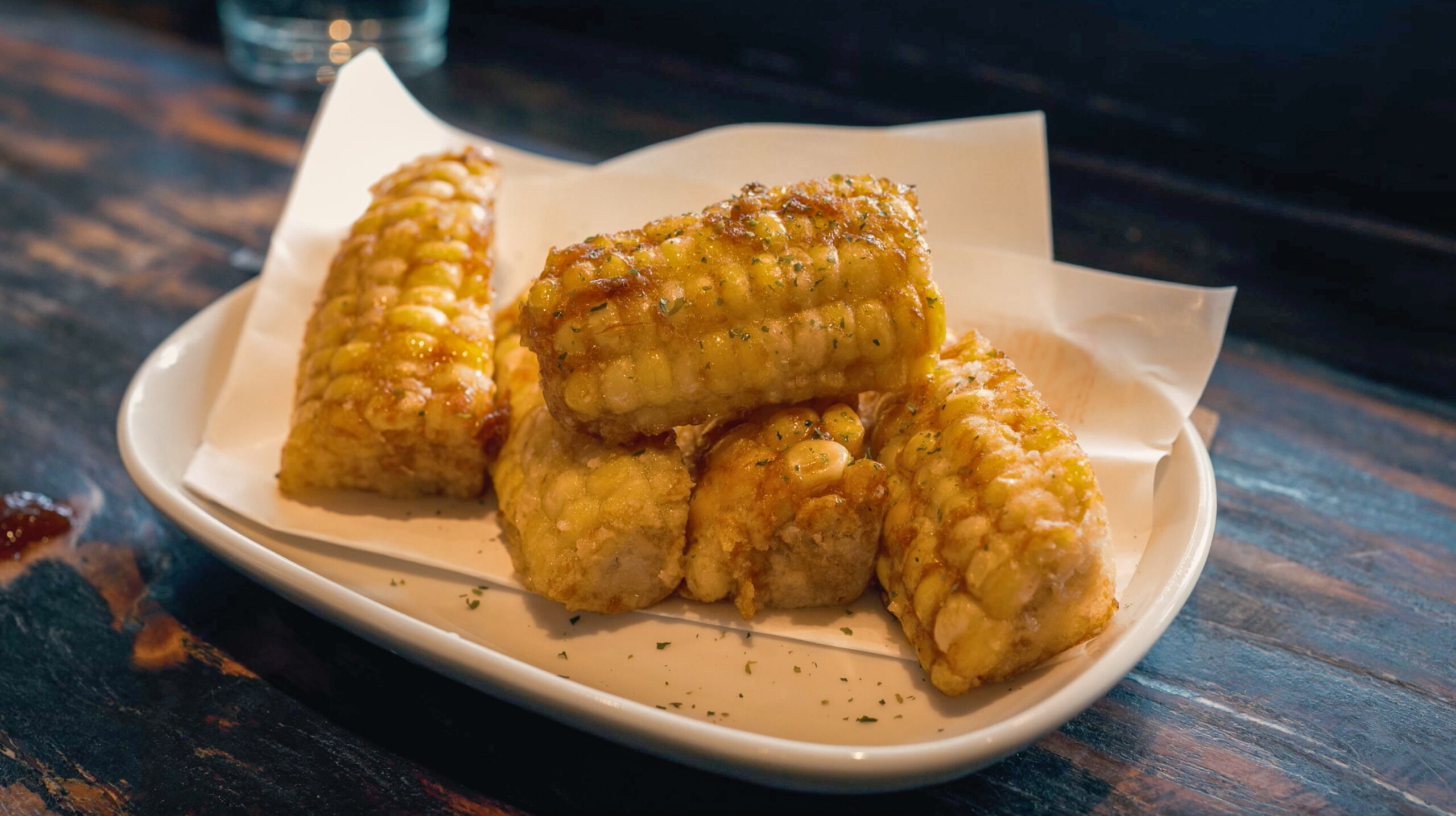 Plate of grilled corn rounds served on a white dish at Kingyo Izakaya in Vancouver, styled for izakaya dining.
