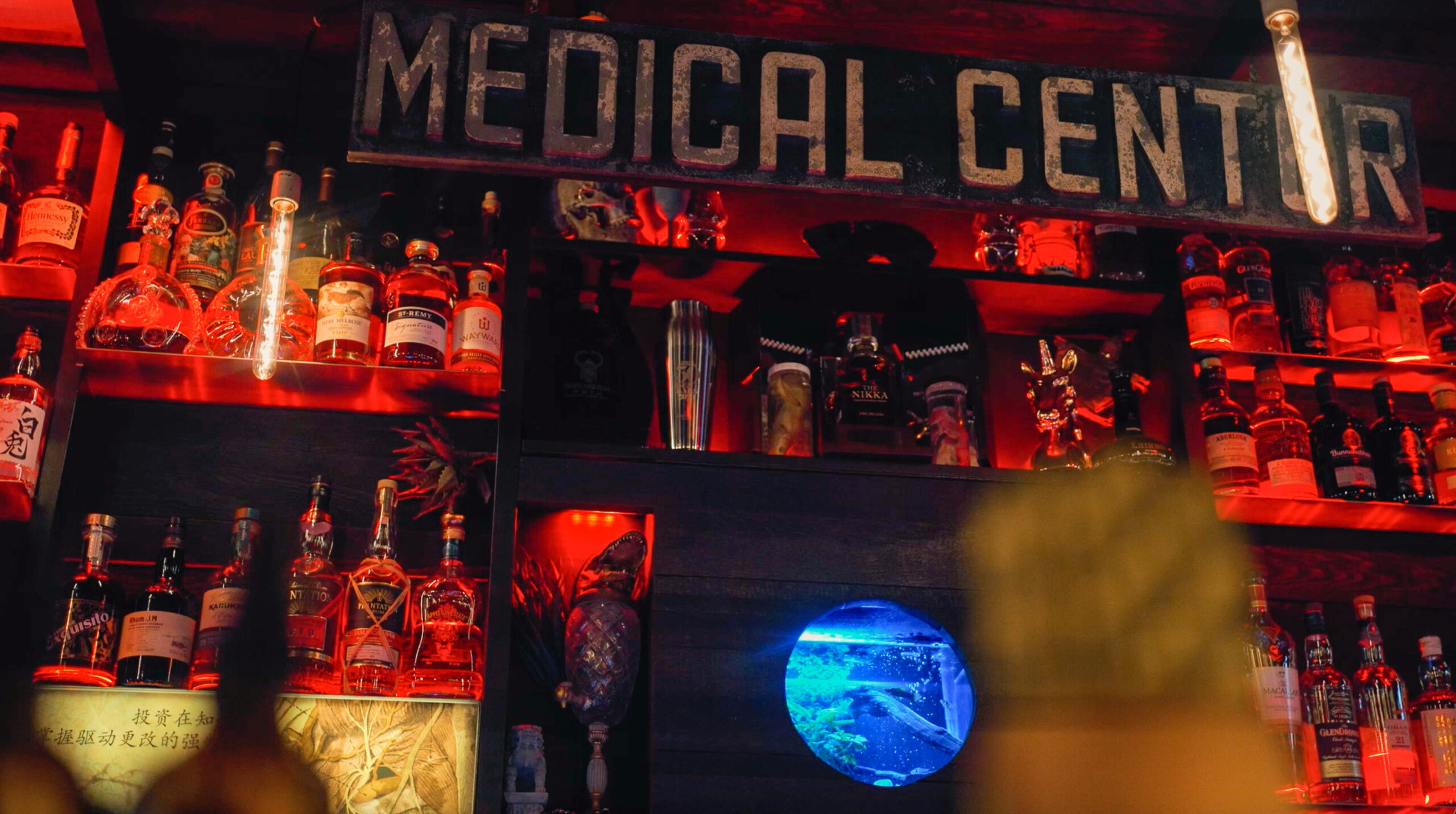 Moody red-lit bar interior with “Medical Center” sign overhead at Keefer Bar.