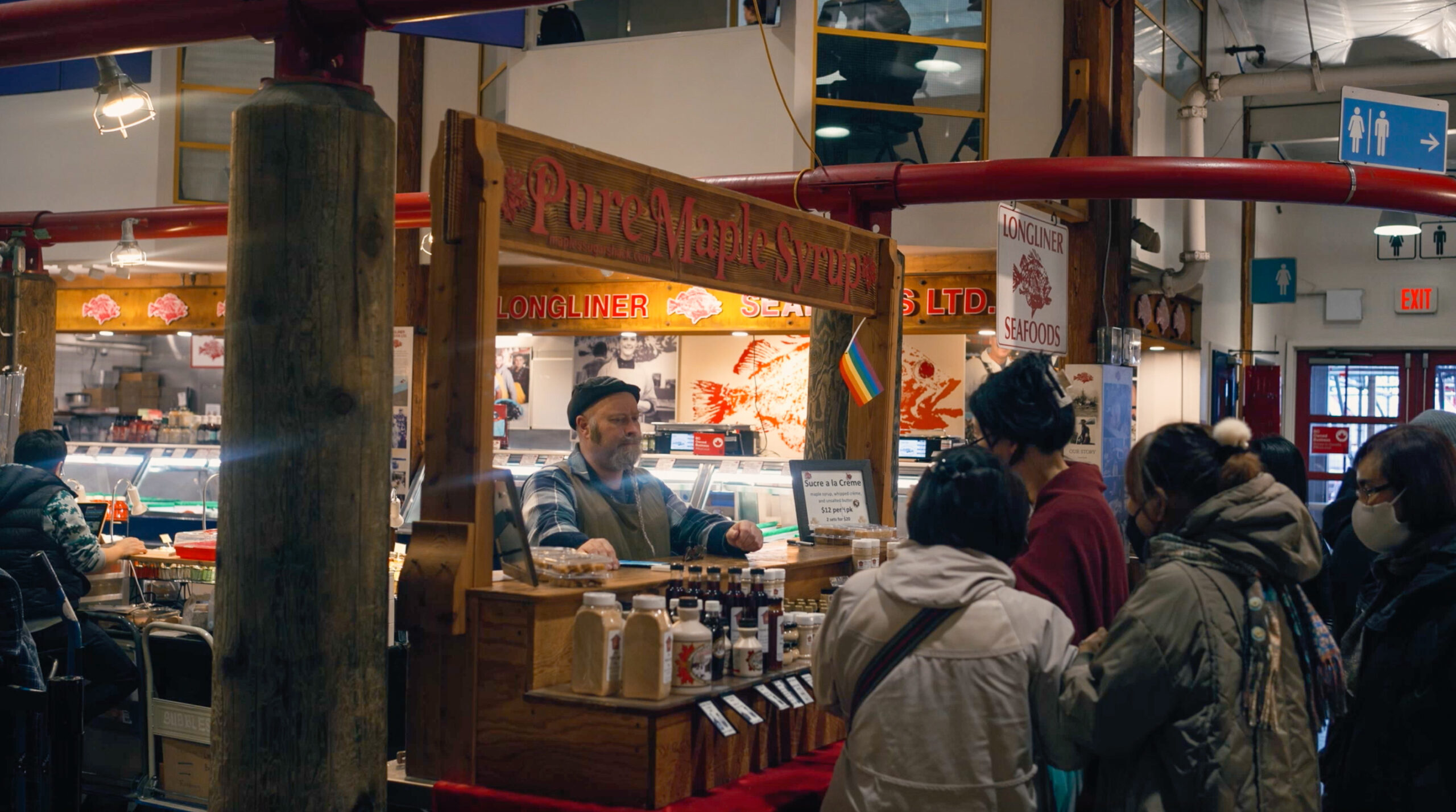 Food vendor stall at Granville Island Market with a staff member serving guests.