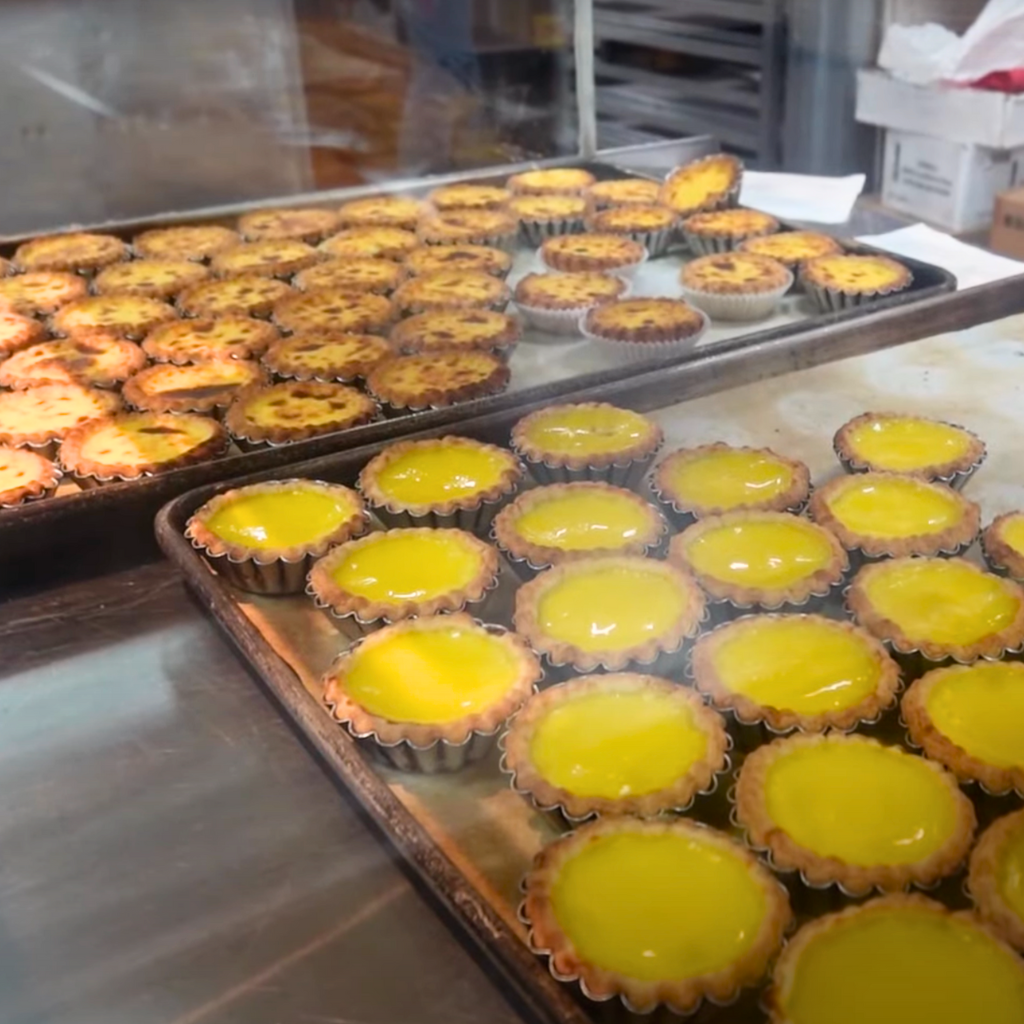 Trays of freshly baked golden egg tarts on display at Double Crispy Bakery in Chinatown.
