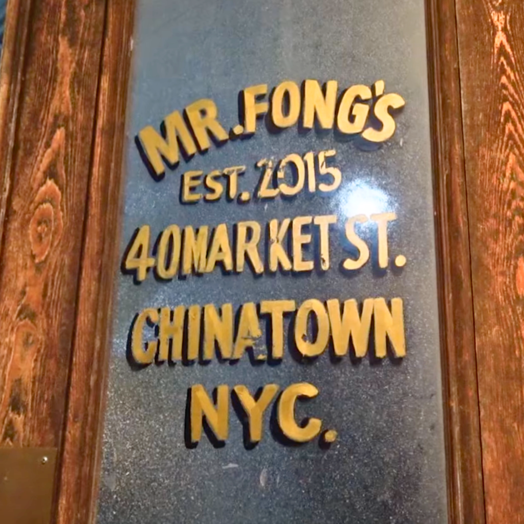 Close-up of the entrance sign at Mr Fong's in Chinatown, showing gold lettering on a textured black background.