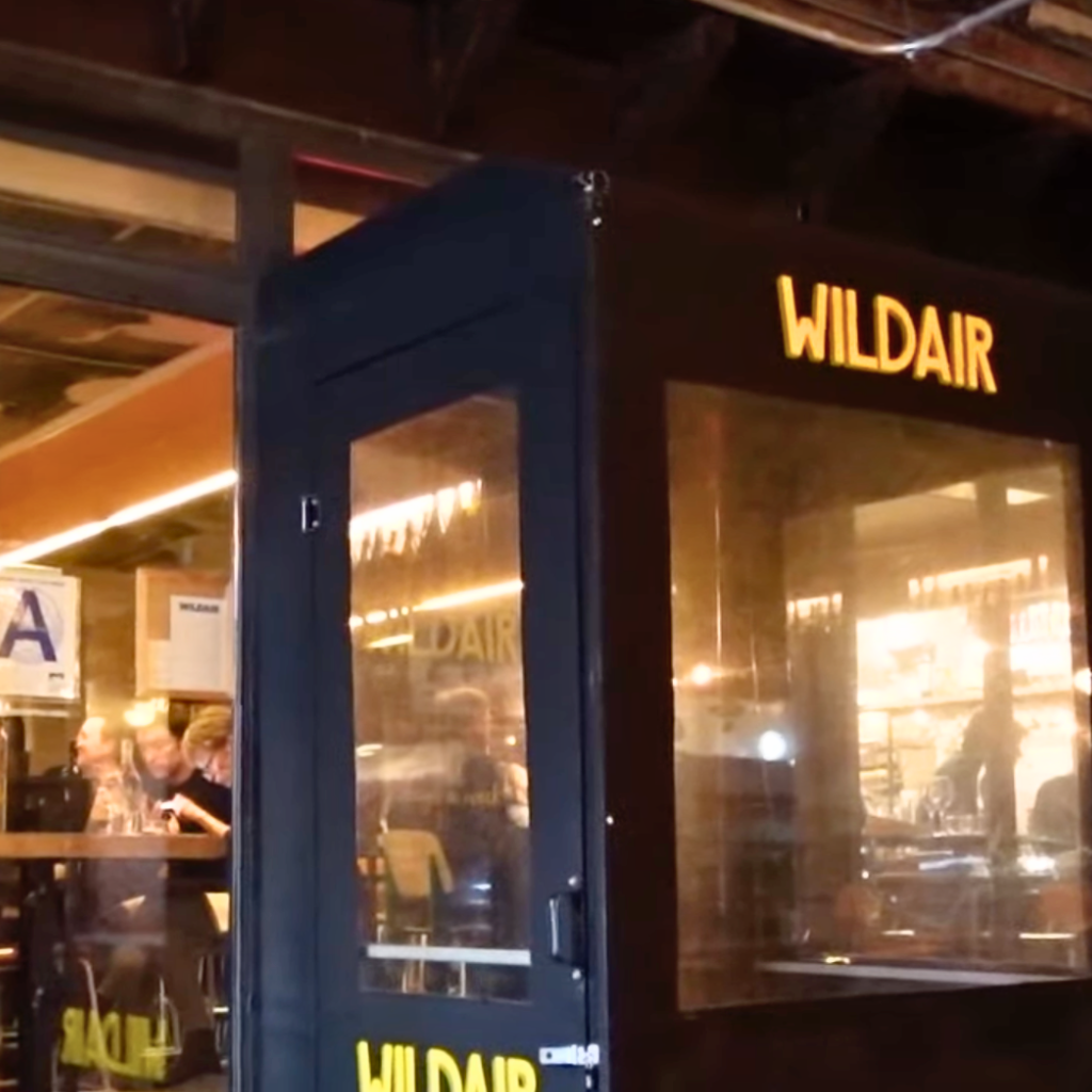 Front entrance of Wildair with glass doors and warm interior lighting visible from the street.