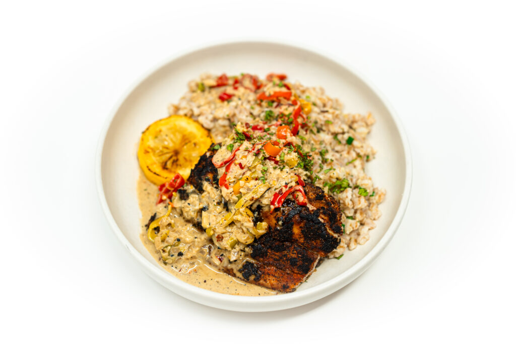Seared blackened mahi mahi fillet topped with a golden creamy habanada pepper sauce, garnished with chopped chives on a white plate
