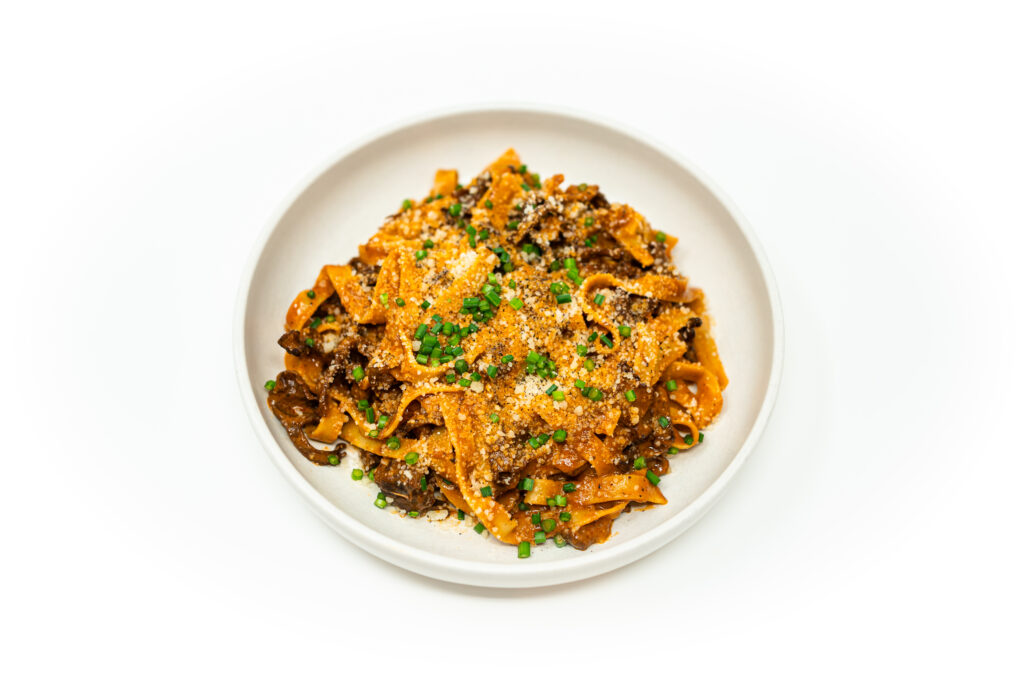 Tagliatelle pasta with braised oxtail and chanterelle mushrooms, topped with grated Parmesan and fresh herbs.