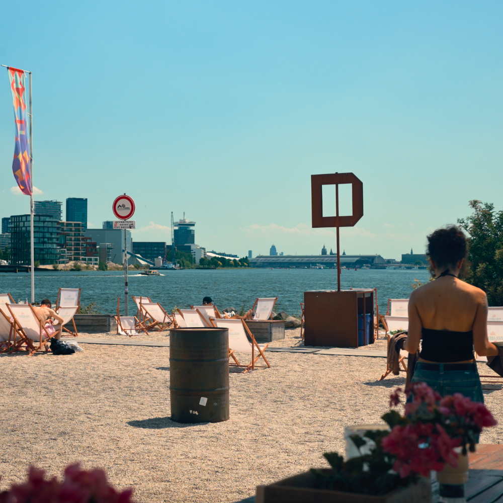 Pllek in Amsterdam Noord, a beachside bar and restaurant with city skyline views and casual summer seating.