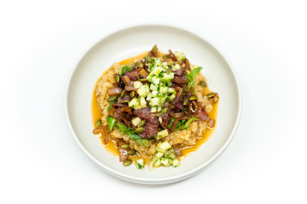 Ahi tuna poke bowl served over sushi rice and arugula, topped with caramelized shallots, cucumber, pepitas, and drizzled with rosé vinaigrette.