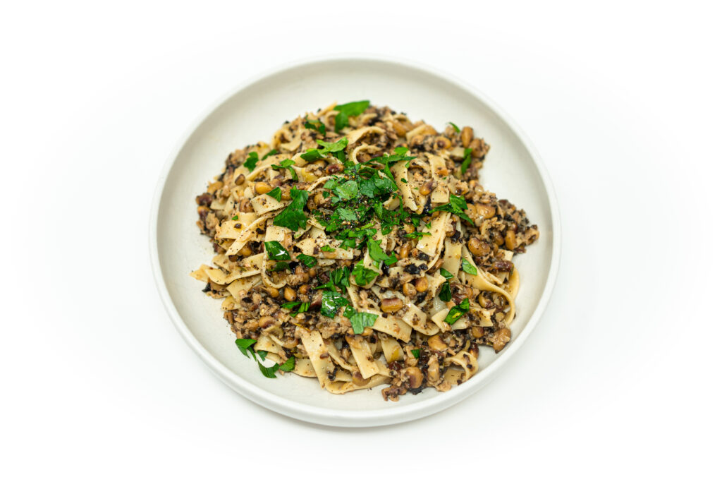 Tagliatelle pasta tossed with a rich vegan ragù of pink-eyed peas and wild mushrooms, finished with parsley and black pepper.