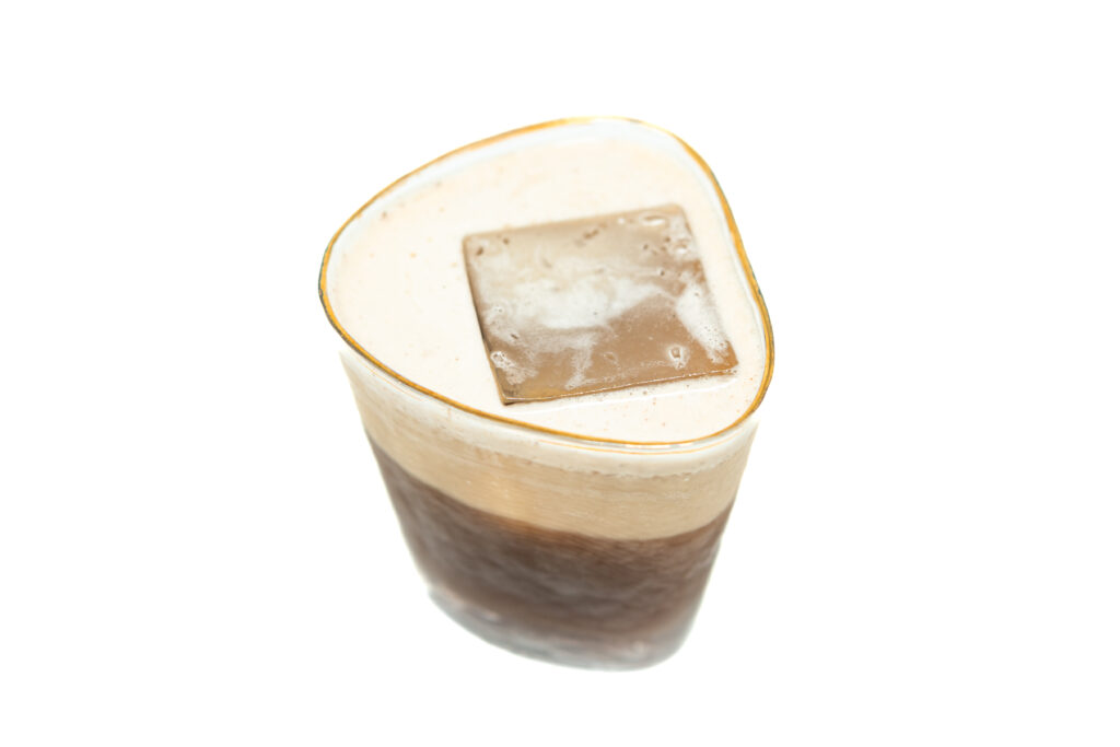 A layered tequila coffee cocktail in a rocks glass topped with whipped cream and cocoa powder