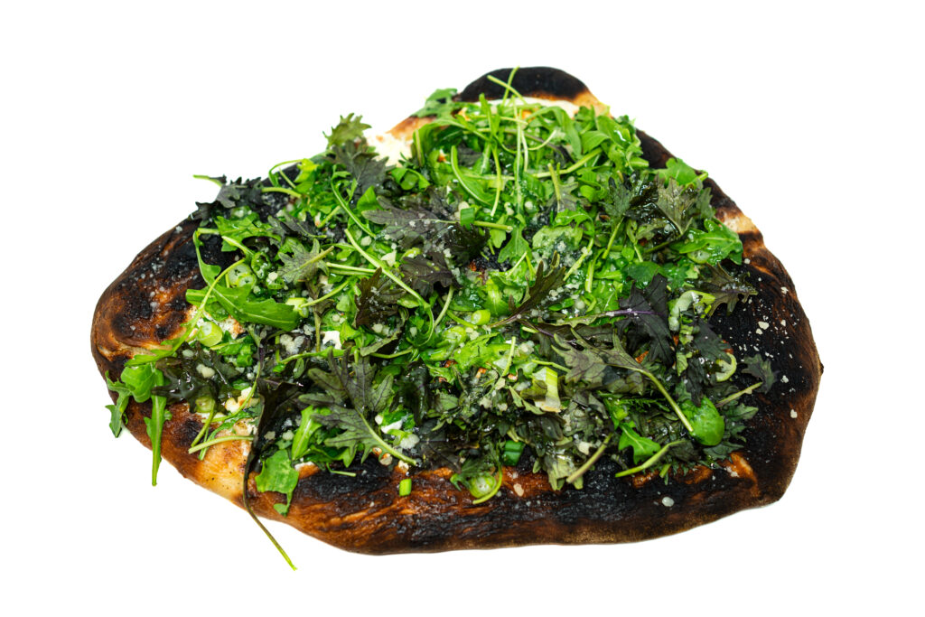 White pizza topped with arugula, baby kale, and green onion, fresh from the oven with melted mozzarella and a golden blistered crust