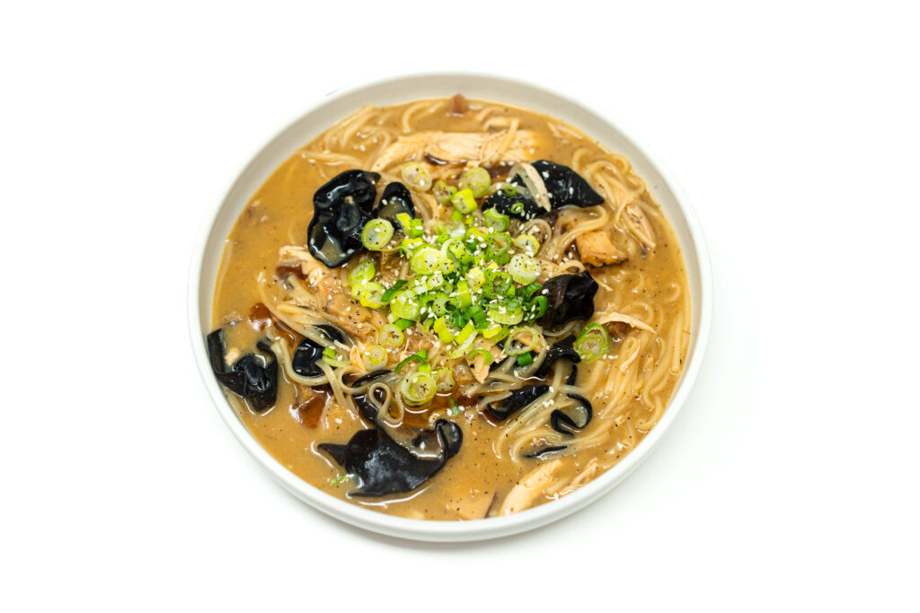 Bowl of miso butter chicken udon noodles topped with green onions and sesame seeds in a creamy miso broth