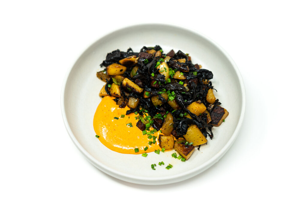 Crispy golden potatoes with seared wild mushrooms topped with a silky paprika aioli and fresh herbs on a rustic plate