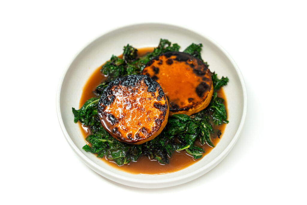 Charred butternut squash rounds served over wilted kale with a glossy miso agrodolce sauce.