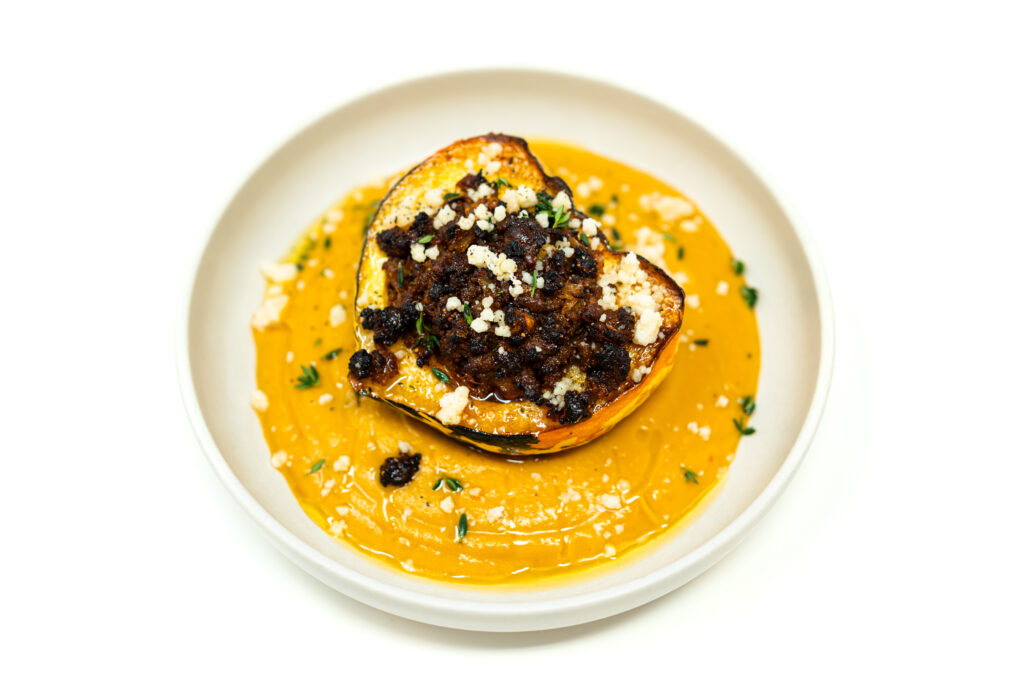 Cut open carnival squash stuffed with spiced ground lamb resting over a silky squash purée with Parmesan and thyme.