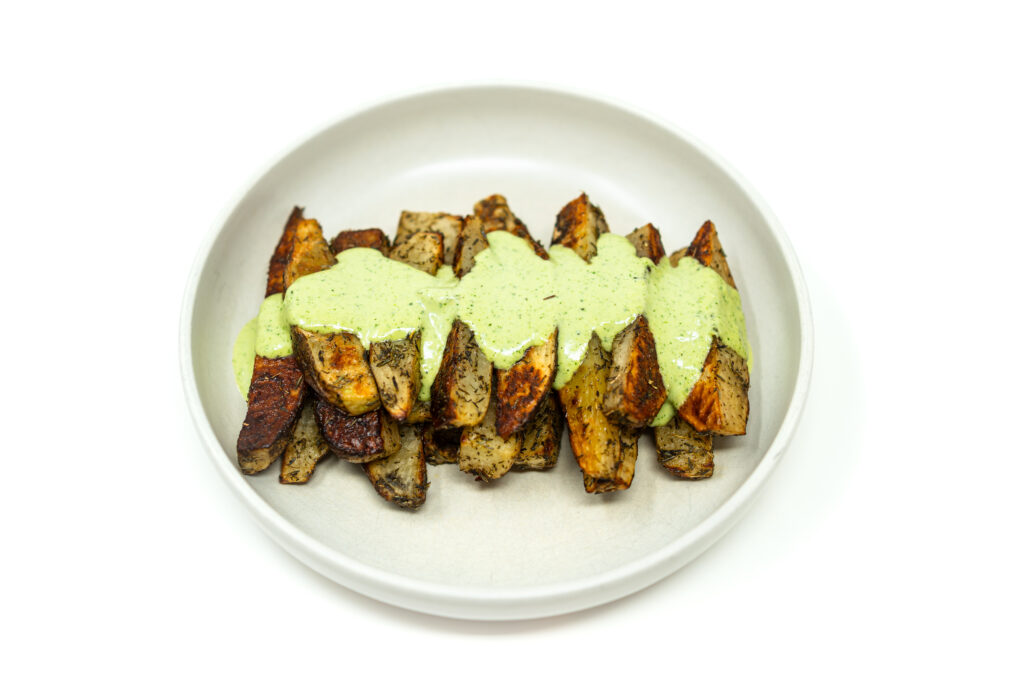 Crispy roasted russet potatoes with golden edges, drizzled with creamy green jalapeño herb sauce and sprinkled with thyme.