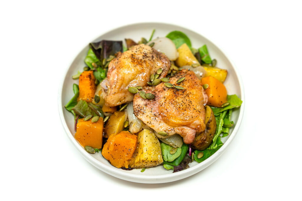 Roasted chicken thighs with golden squash, potatoes, and shallots served over fresh greens with vinaigrette.
